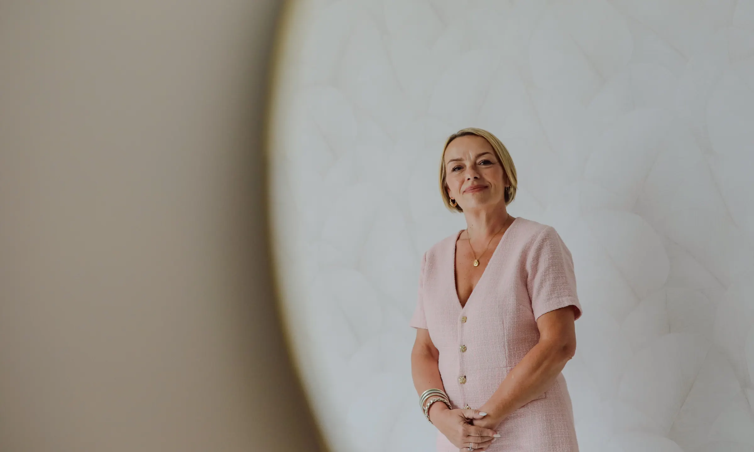 Stéphanie Bariant, souriante, les mains jointes, devant un mur clair